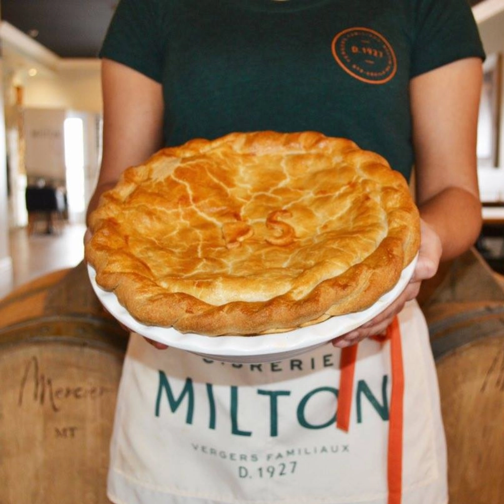 Personne tenant une tarte artisanale fraîchement cuite.