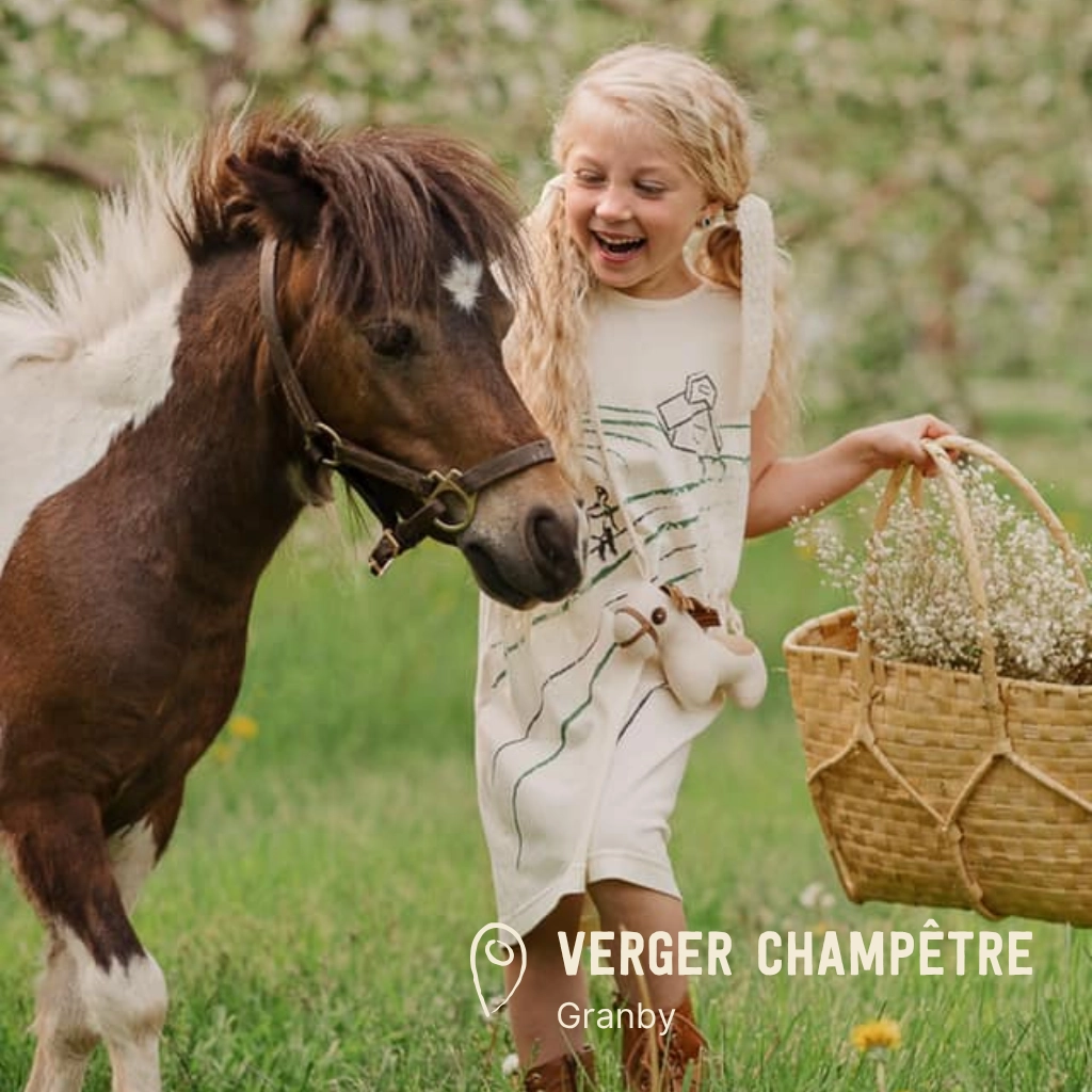 Enfant riant avec un poney dans un verger.